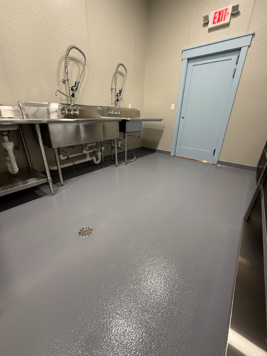 Gray epoxy floor at a stainless wash station in a commercial kitchen with floor drain