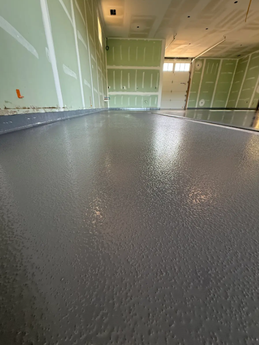 Solid gray epoxy floor coating in a new-build industrial space with unfinished walls