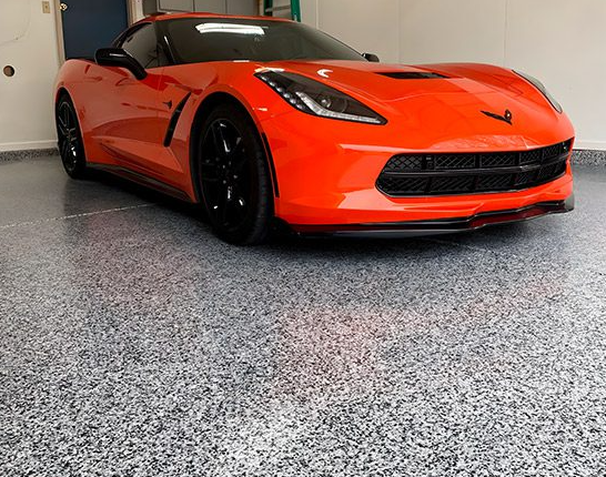 Gray flake epoxy garage floor with an orange Corvette parked on it