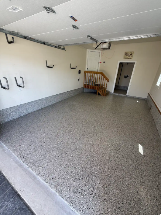 Tan and brown flake epoxy floor in a two-car residential garage with wall storage hooks