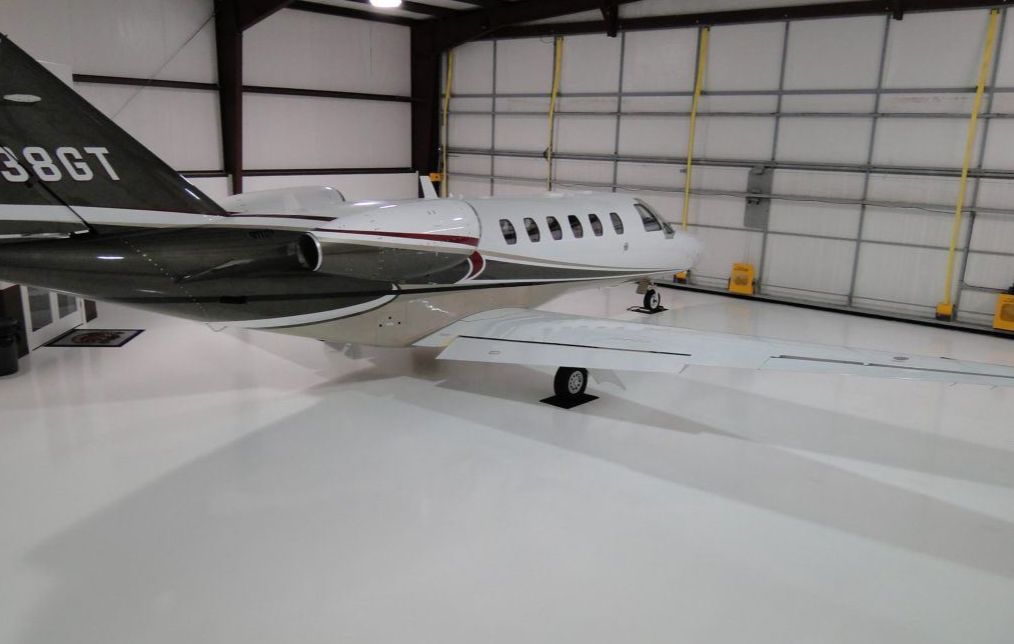 Private jet parked on a high-gloss white epoxy floor in an aircraft hangar
